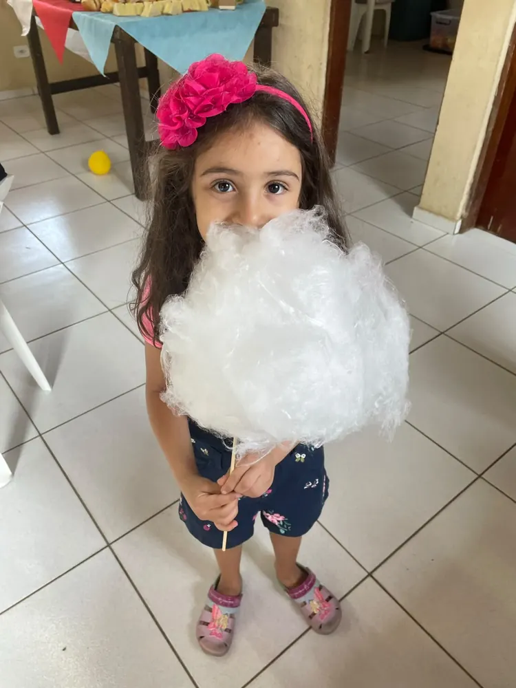 Menina segurando um algodão doce feito na hora na festa