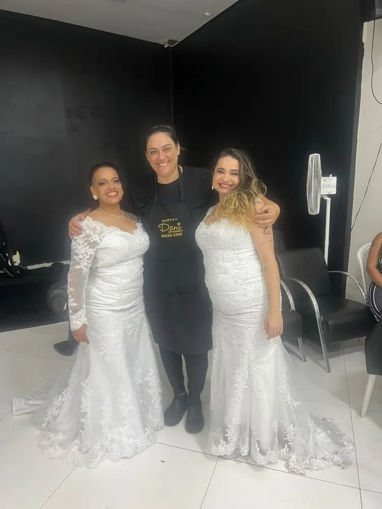 A Daniela entre as duas noivas, de vestido branco, antes da festa