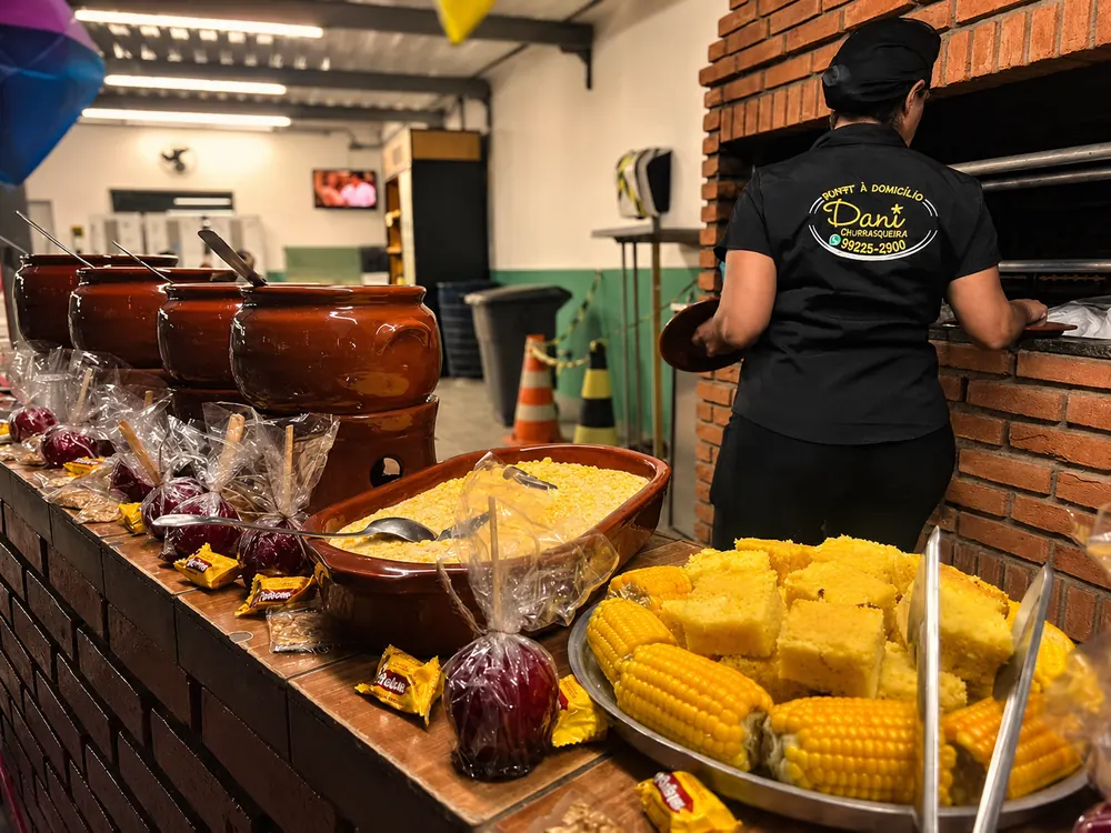 Mesa junina com milho, quentão e doces